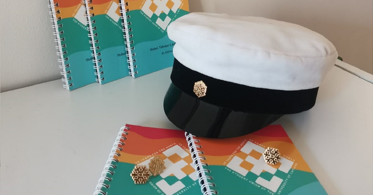 ylioppilaslakki Kide-kokardilla ja laulukirjoja