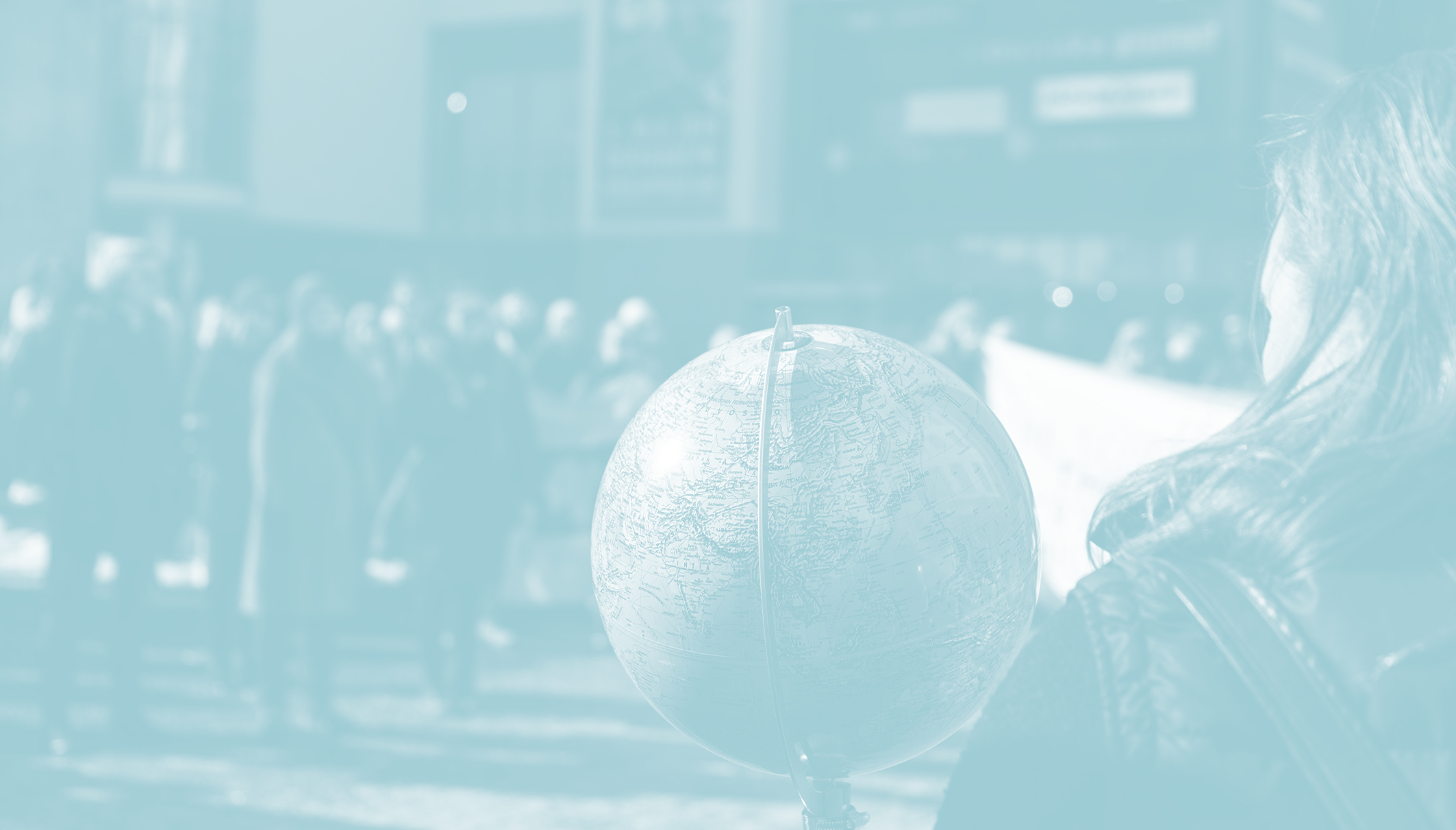 Student holding a globe in front of people at the city centre.